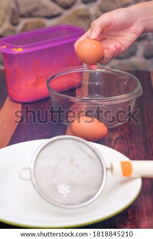 Female hands holding cracked egg over a clear  bowl. The making of cake.
