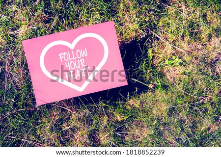 Follow your heart message written on paper on green grass background. Inspirational quote for motivation, happiness or success in relationships or life.