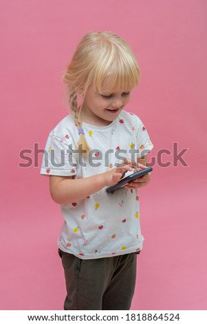 Portrait of little  girl using smartphone with copy space isolated on pink background. Happy small toddler girl education internet technology, back to school concept banner