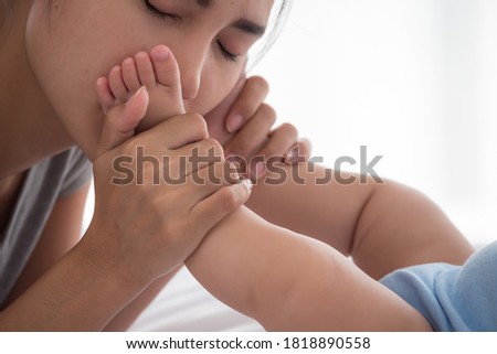 Mother kissing on newborn baby foot.