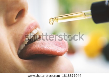 herbal alternative medicine and dietary supplements - woman taking cbd hemp oil drops in mouth from dropper. medical cannabis Royalty-Free Stock Photo #1818891044