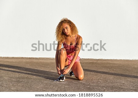 Young girl with curly hair doing sport outdoors with sport clothes