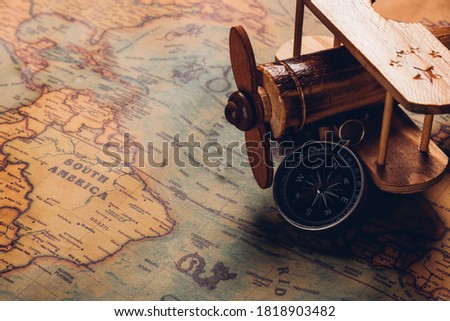 Old compass discovery and wooden plane on vintage paper antique world map background, Retro style cartography travel geography navigation