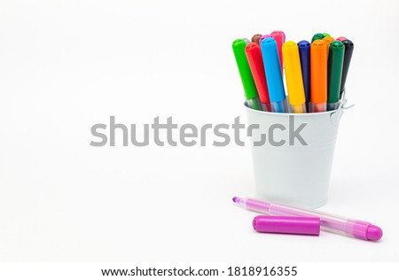 Group of multicolored markers in a white metal bucket on light background, one pen open cup, copy space. Drawing felt-tip pens, pencils, artists tools, creativity, hobby. Colorful school supplies. Royalty-Free Stock Photo #1818916355