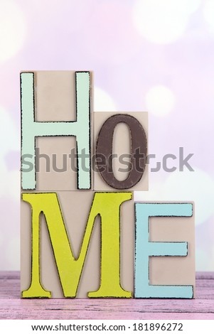 Decorative letters forming word HOME on table on bright background