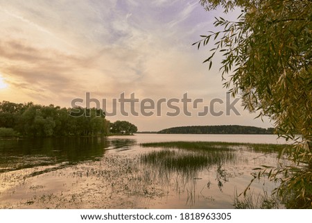 Early autumn evening landscape. Sunset over a lake surrounded by trees.