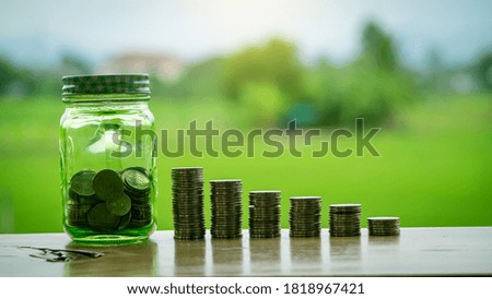 Piles of coins arranged like graphs and piggy banks on a green background table.