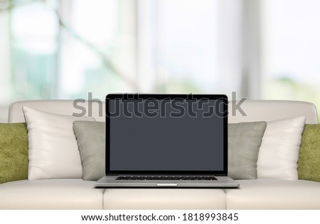 Blank screen on laptop computer on a couch at modern home
