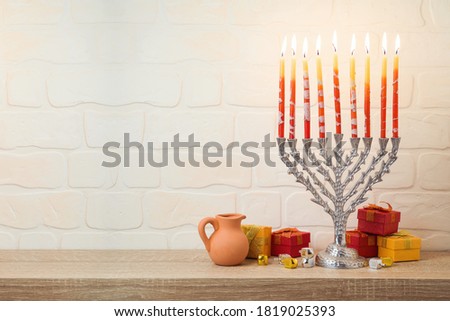 Jewish holiday Hanukkah concept with menorah, gift box and spinning top on wooden table