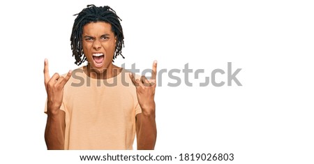 Young african american man wearing casual clothes shouting with crazy expression doing rock symbol with hands up. music star. heavy concept. 