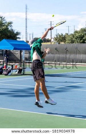 Boy playing in a tennis match making a serve of the ball