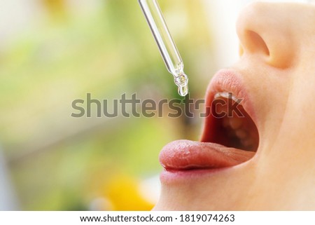 woman taking vitamin d drops in mouth from dropper. copy space Royalty-Free Stock Photo #1819074263