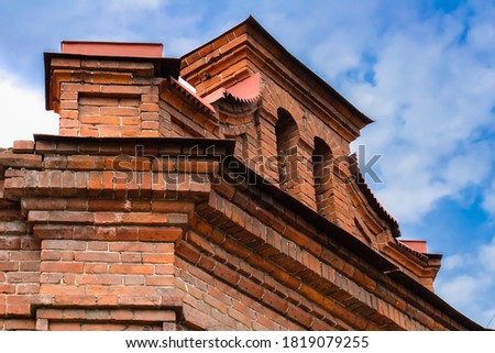 Parapet on the roof of an old brick building against a blurred background of blue sky with clouds. Royalty-Free Stock Photo #1819079255