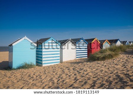 A row of colourful beach huts under a blue sky at Southwold beach in England Royalty-Free Stock Photo #1819113149