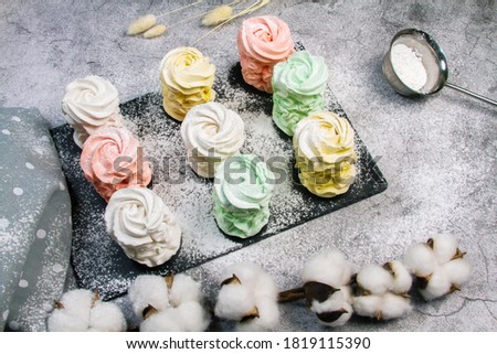 Flat lay with a plate of home-made marshmallows (zephyr, meringue) made with apple and mint, sweet, airy, on a gray background, cakes sprinkled with powdered sugar, beautiful festive background.
