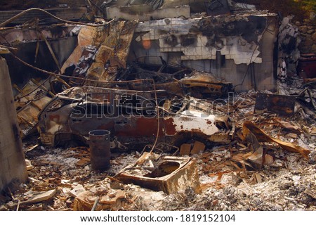 The remains of a high-end home completely destroyed by wildfire in California, with two demolished cars, a washing machine and charred debris Royalty-Free Stock Photo #1819152104