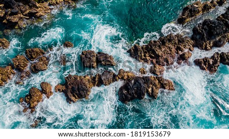 Stones, turquoise waves and sea foam from above. Atlantic ocean coastline with rocks. Madeira island, Portugal. Aerial drone photography. Beautiful landscape. Scenery outdoor background.  