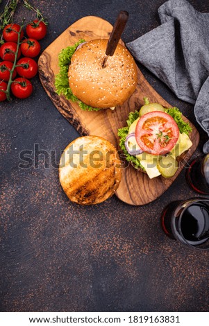 Burger and cheeseburger with tomato on dark background