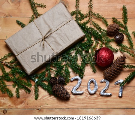 wooden table with a Christmas composition with a gift, Christmas silver decorations, pine cones. fingers 2021. Copy cpace, Flat lay, top view