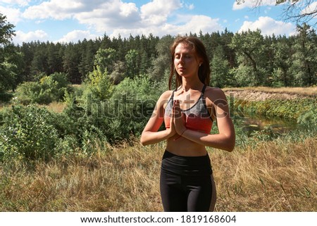 Beautiful young woman in dress meditating on the nature. Summertime, mind detox and yoga concept