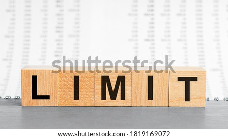 LIMIT word made with building blocks. Limit on wooden cubes on grey notepad. Business concept