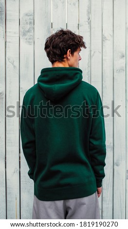 City portrait of handsome young guy wearing green (watercolor) blank hoodie or sweatshirt with space for your logo or design. Mockup for print Royalty-Free Stock Photo #1819190270