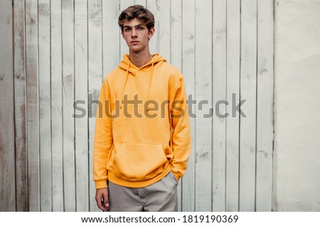 City portrait of handsome young guy wearing yellow blank hoodie or sweatshirt with space for your logo or design. Mockup for print