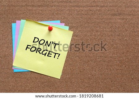 A stack of memo notes written with Don't Forget on a cork board.