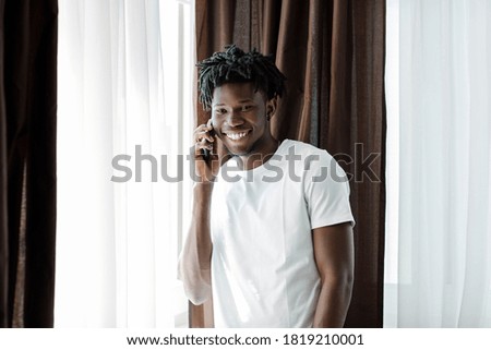 Overjoyed african American millennial man laugh having pleasant cellphone conversation, happy biracial male smile involved in smartphone call, talking using modern gadget, good connection concept.