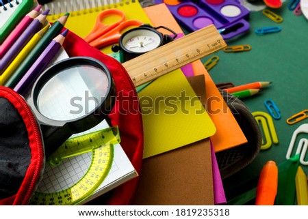 Colorful school supplies in red color school bag on green background,education concept