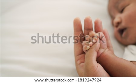 african american new born baby hand holding mom finger on white bed Royalty-Free Stock Photo #1819247924