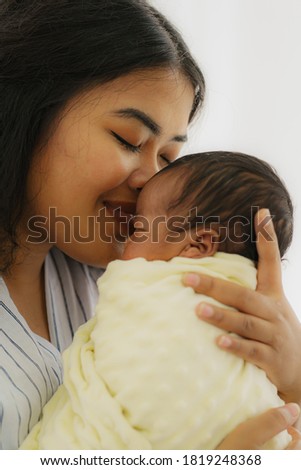 mixed race african american and asian mother gentle kiss her newborn baby with happy face