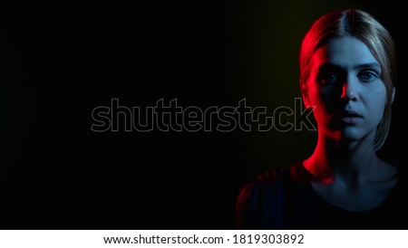 Female silhouette portrait. Feeling helpless. Worried woman in neon light glow looking at camera isolated on black cope space. Psychology support. Stuck problem. Toxic relationship
