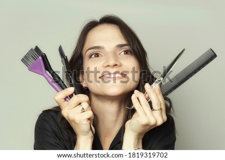 portrait of a beautiful young brunette girl with combs and scissors. hairdresser concept.