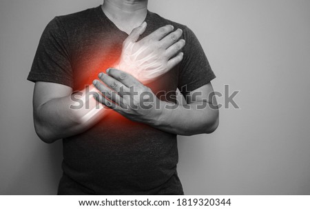 A black and white image Closeup of male arms holding his painful wrist  From arthritis symptoms or Carpal Tunnel Syndrome (CST) Medical healthcare concept.