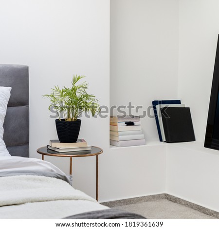 White bedroom with round bedside table with decorations and books on shelf in wall
