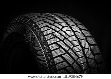 winter tire, friction for snow and ice. asymmetrical tread pattern. close-up on a black background. Royalty-Free Stock Photo #1819384679