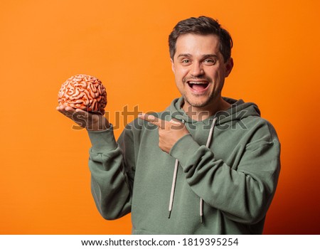 Young smiling  with a brain on orange background 