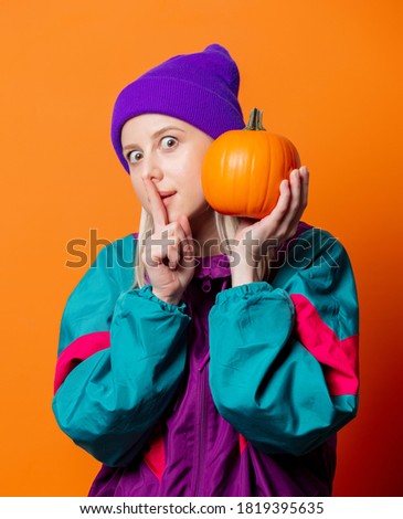 Style woman in 90s tracksuit with pumpkin on orange background