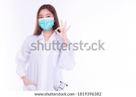 Professional young woman doctor wear uniform coat and mask while make hand sign ok for good job over isolated white background. Healthy care and medical concept.