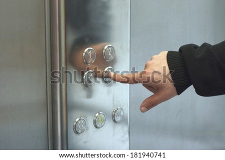 Man pressing elevator button inside modern elevator