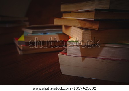 Stacks of books on wood table in the dim light