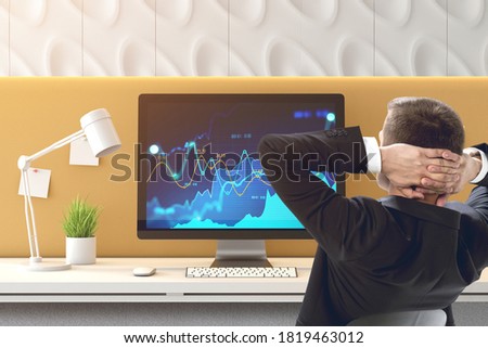 Rear view of confident young businessman looking at charts on his computer screen in modern office. Concept of investment and success. Toned image