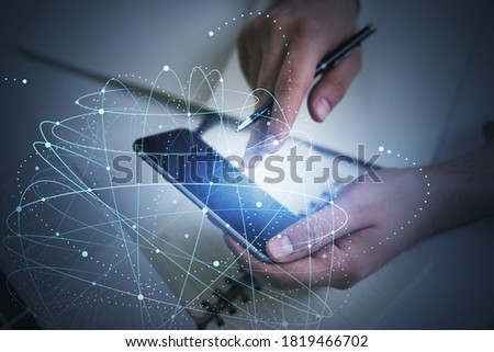 Hands of businessman using smartphone in blurry office with double exposure of network interface. Toned image