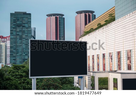 Large billboards stand in a crowded place. Surrounded by tall buildings.