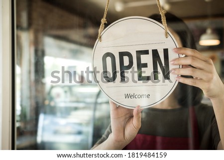 Reopen. waitress woman turning open sign board reopen after coronavirus quarantine is over in modern cafe coffee shop ready to service, cafe restaurant, small business owner, food and drink concept