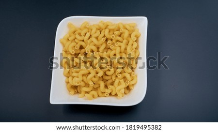 small spring-shaped pasta. Pasta in a white plate, a plate with macaroni on a dark table