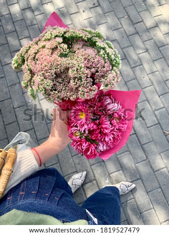 Two colorful bouquets with pink paper in hand 