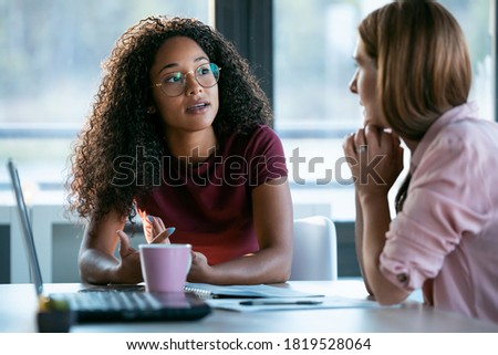 Shot of two beautiful business women working together with laptop while talking about job news in the office. Royalty-Free Stock Photo #1819528064