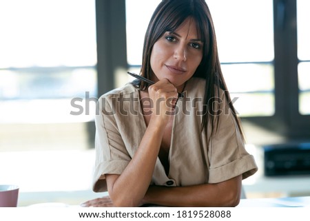 Portrait of smart beautiful young businesswoman looking at camera sitting in the office.